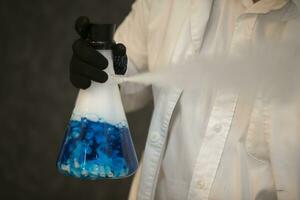 Chemical flask with a blue solution in the hands of a laboratory assistant. Experiences and experiments. photo