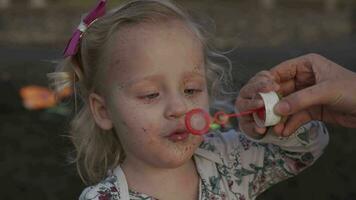 A slowmotion of an adorable little girl who is blowing soap bubbles video