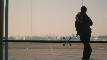 une vue arrière de une homme permanent suivant à une énorme aéroport fenêtre video