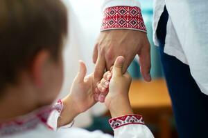 el mano de un adulto sostiene el mano de un niño, ellos son vestido en étnico eslavo ropa. foto