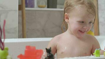 poco ragazza giocando nel il bagno e spruzzi acqua video