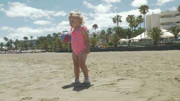 Cute baby girl in pink swimsuit walking on the beach video