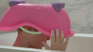 imaginativo criança usando brinquedo banheira Como capacete jogando dentro a banho video