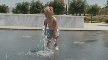 Little child playing with water jet of street fountain video