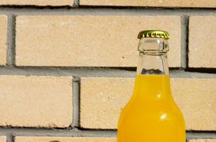 Glass Lemonade Bottle against the backdrop of a brick wall. Closeup Photography for Banner, Promotion, Ptinting, Poster. Fresh and juicy non-alcoholic Summer drink With metal cup. photo