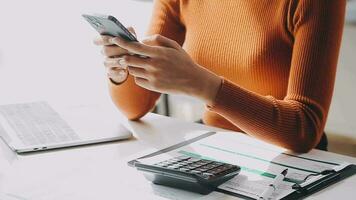 mujer de negocios asiática que usa una computadora portátil y trabaja en la oficina con un documento de calculadora en el escritorio, planificando el análisis del informe financiero, la inversión del plan de negocios, el concepto de análisis financiero. video