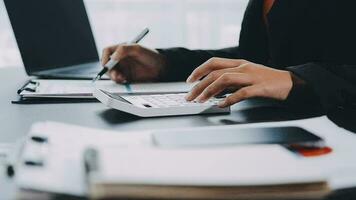 Asian Businesswoman Using laptop computer and working at office with calculator document on desk, doing planning analyzing the financial report, business plan investment, finance analysis concept. video