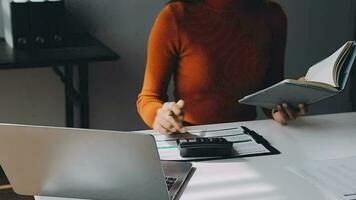 Asian Businesswoman Using laptop computer and working at office with calculator document on desk, doing planning analyzing the financial report, business plan investment, finance analysis concept. video