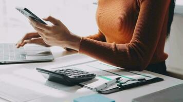 Asian Businesswoman Using laptop computer and working at office with calculator document on desk, doing planning analyzing the financial report, business plan investment, finance analysis concept. video