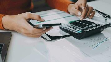 Asian Businesswoman Using laptop computer and working at office with calculator document on desk, doing planning analyzing the financial report, business plan investment, finance analysis concept. video