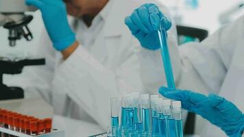 Health care researchers working in life science laboratory. Young female research scientist and senior male supervisor preparing and analyzing microscope slides in research lab. video