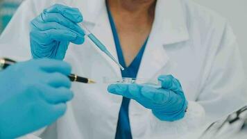 Health care researchers working in life science laboratory. Young female research scientist and senior male supervisor preparing and analyzing microscope slides in research lab. video