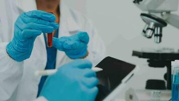 Health care researchers working in life science laboratory. Young female research scientist and senior male supervisor preparing and analyzing microscope slides in research lab. video