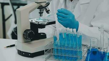 Health care researchers working in life science laboratory. Young female research scientist and senior male supervisor preparing and analyzing microscope slides in research lab. video