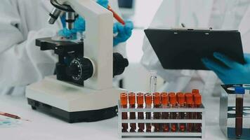 Health care researchers working in life science laboratory. Young female research scientist and senior male supervisor preparing and analyzing microscope slides in research lab. video