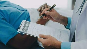 Doctor and patient sitting and talking at medical examination at hospital office, close-up. Therapist filling up medication history records. Medicine and healthcare concept. video