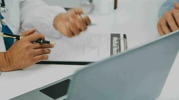 Doctor and patient sitting and talking at medical examination at hospital office, close-up. Therapist filling up medication history records. Medicine and healthcare concept. video