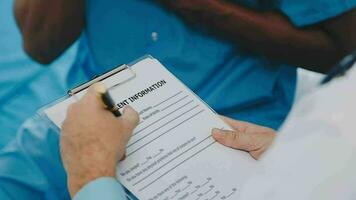 médico y paciente sentado y hablando a médico examen a hospital oficina, de cerca. terapeuta relleno arriba medicación historia registros. medicina y cuidado de la salud concepto. video