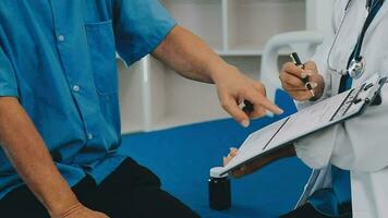 Doctor and patient sitting and talking at medical examination at hospital office, close-up. Therapist filling up medication history records. Medicine and healthcare concept. video