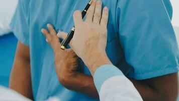 Doctor and patient sitting and talking at medical examination at hospital office, close-up. Therapist filling up medication history records. Medicine and healthcare concept. video