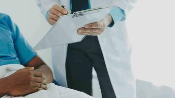 Doctor and patient sitting and talking at medical examination at hospital office, close-up. Therapist filling up medication history records. Medicine and healthcare concept. video