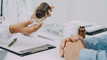 Doctor and patient sitting and talking at medical examination at hospital office, close-up. Therapist filling up medication history records. Medicine and healthcare concept. video