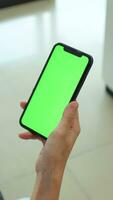 hand innehav mobil telefon med grön skärm på Hem, använder sig av telefon grön skärm, grön skärm, smartphone grön skärm video