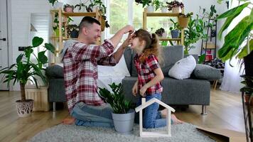 Incomplete family dad and daughter are enjoying new home, sitting on sofa. Mortgage, insurance and protection, buying and moving into your own home, green house with potted plant video