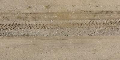 panorama of road from above on surface of gravel road with car tire tracks in countryside photo