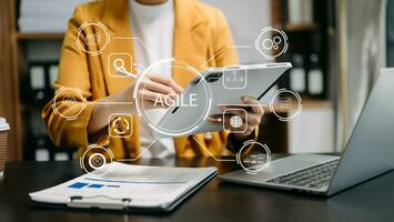 ágil desarrollo metodología concepto. negocio mano utilizando ordenador portátil computadora y tableta con virtual pantalla ágil icono en moderno oficina digital tecnología concepto. foto