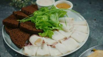 lard with black bread and greens on a plate, restaurant appetizer close up video