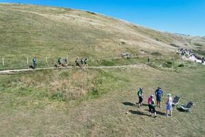 High Angle View of People are Approaching to Durdle Door Beach Which is Most Famous Tourist Attraction Place Through Walking Distance over Landscape and Hills. Captured on September 9th, 2023 photo