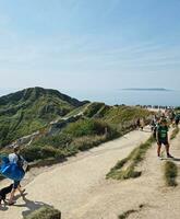 alto ángulo ver de personas son que se acerca a durdle puerta playa cuales es más famoso turista atracción sitio mediante caminando distancia terminado paisaje y sierras. capturado en septiembre 9, 2023 foto