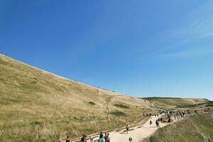 High Angle View of People are Approaching to Durdle Door Beach Which is Most Famous Tourist Attraction Place Through Walking Distance over Landscape and Hills. Captured on September 9th, 2023 photo