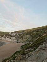 High Angle View of People are Approaching to Durdle Door Beach Which is Most Famous Tourist Attraction Place Through Walking Distance over Landscape and Hills. Captured on September 9th, 2023 photo