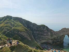 High Angle View of People are Approaching to Durdle Door Beach Which is Most Famous Tourist Attraction Place Through Walking Distance over Landscape and Hills. Captured on September 9th, 2023 photo