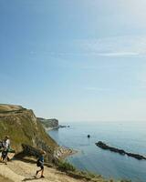 High Angle View of People are Approaching to Durdle Door Beach Which is Most Famous Tourist Attraction Place Through Walking Distance over Landscape and Hills. Captured on September 9th, 2023 photo