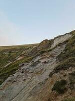 High Angle View of People are Approaching to Durdle Door Beach Which is Most Famous Tourist Attraction Place Through Walking Distance over Landscape and Hills. Captured on September 9th, 2023 photo