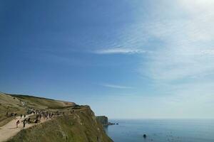 High Angle View of People are Approaching to Durdle Door Beach Which is Most Famous Tourist Attraction Place Through Walking Distance over Landscape and Hills. Captured on September 9th, 2023 photo