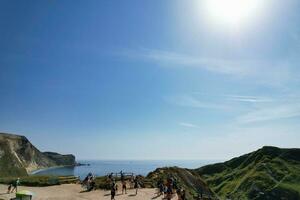 High Angle View of People are Approaching to Durdle Door Beach Which is Most Famous Tourist Attraction Place Through Walking Distance over Landscape and Hills. Captured on September 9th, 2023 photo