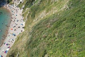 High Angle View of People are Approaching to Durdle Door Beach Which is Most Famous Tourist Attraction Place Through Walking Distance over Landscape and Hills. Captured on September 9th, 2023 photo