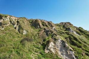 High Angle View of People are Approaching to Durdle Door Beach Which is Most Famous Tourist Attraction Place Through Walking Distance over Landscape and Hills. Captured on September 9th, 2023 photo