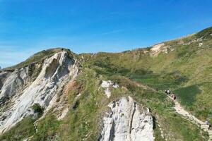 High Angle View of People are Approaching to Durdle Door Beach Which is Most Famous Tourist Attraction Place Through Walking Distance over Landscape and Hills. Captured on September 9th, 2023 photo