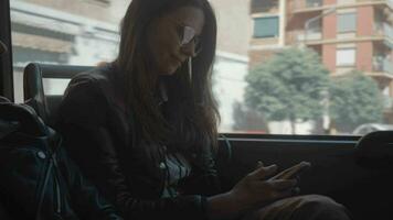 A longhaired girl in sunglasses sitting in a moving bus video