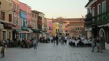 levendig straat in Burano met mensen in buitenshuis cafés, Italië video