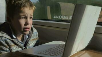 Child traveling by train and watching movie on laptop video