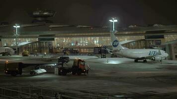 vnukovo aeropuerto a invierno noche, Moscú. nieve arado camiones limpieza pista video