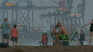 Port with container cranes and crowded beach in Valencia, Spain video