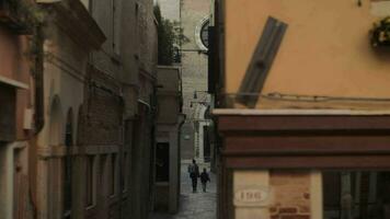 un estrecho Venecia calle con Roca fachadas y un pavimentado cubrir video