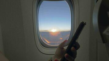 mit Handy, Mobiltelefon im das Flugzeug Flugzeug Fenster mit Sonnenaufgang im Hintergrund video